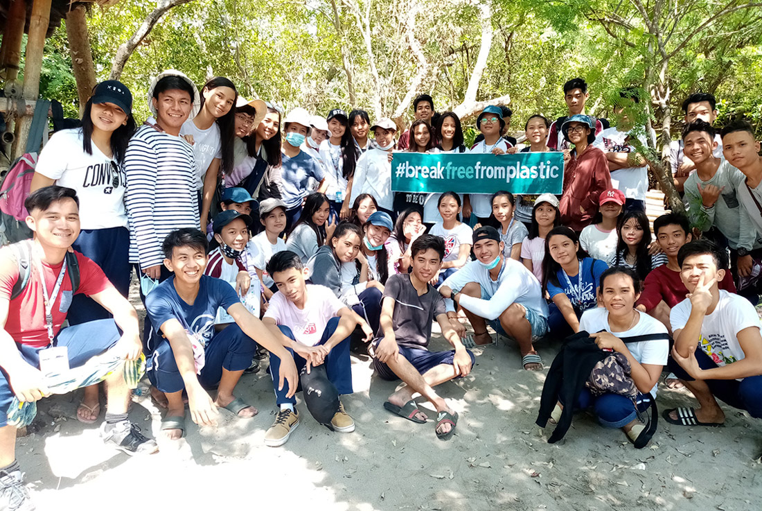 A group of people taking a photo with the #breakfreefromplastic banner during the #BrandAudit2019 in Davao del sur, Philippines.
