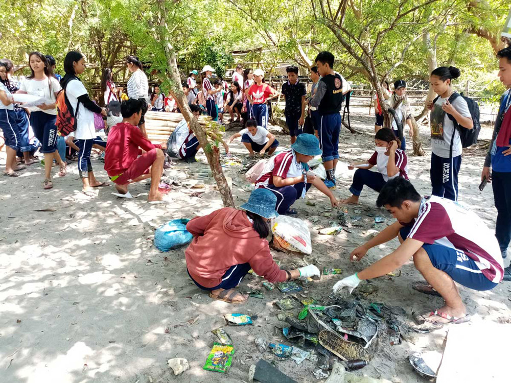 A lot of people are gathered in a shore, some are sorting the trash they have collected during the #BrandAudit2019 in Davao del sur, Philippines.