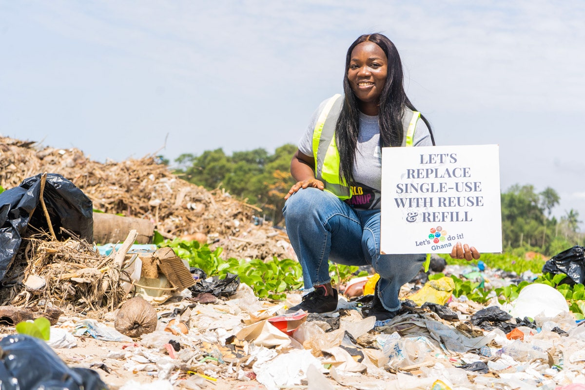 A country leader of Ghana holds up a sign that says "Let's replace single-use plastics with reuse and refill" during a cleanup by Let's Do It Ghana! Photo by Kate Adobaya.