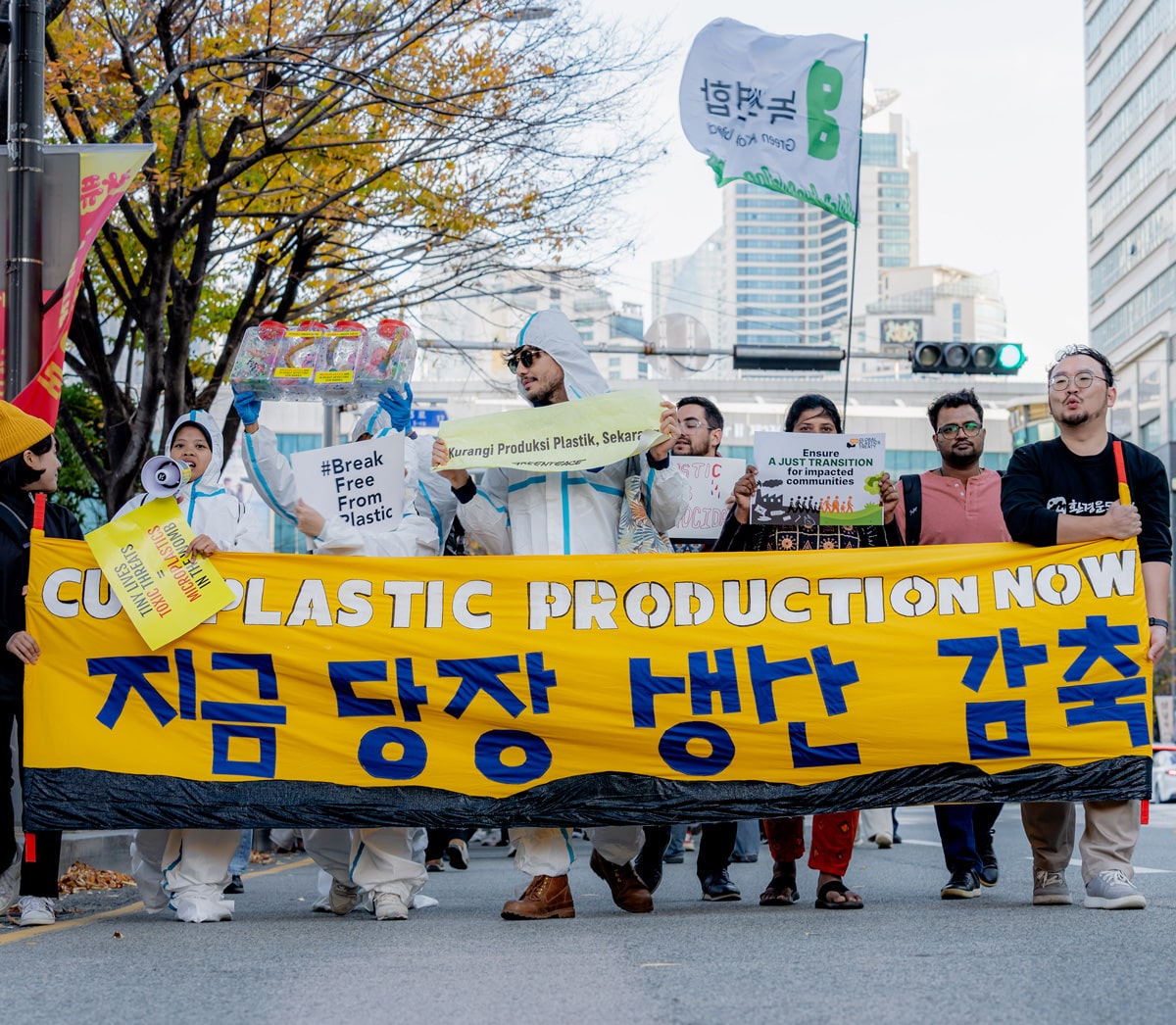 a group of people holding a banner that says cut plastic production now during the INC-5 in Busan, South Korea