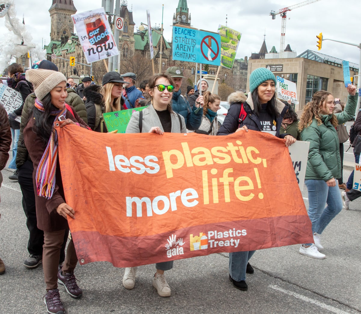a group of people holding a banner that says less plastic, more life during the INC-4
