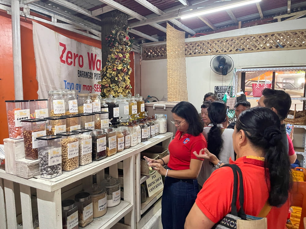ผู้คนกำลังอยู่ในร้านขายสินค้าใช้ซ้ำและเติมใหม่ โดยกำลังดูขวดโหลที่บรรจุอาหารและเครื่องปรุงรสต่างๆ